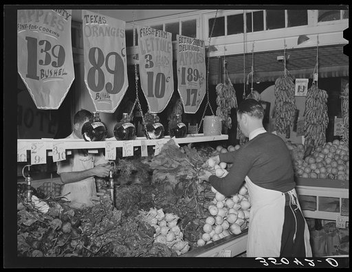 Placing vegetables in display racks at retail grocery store. San Angelo, Texas
