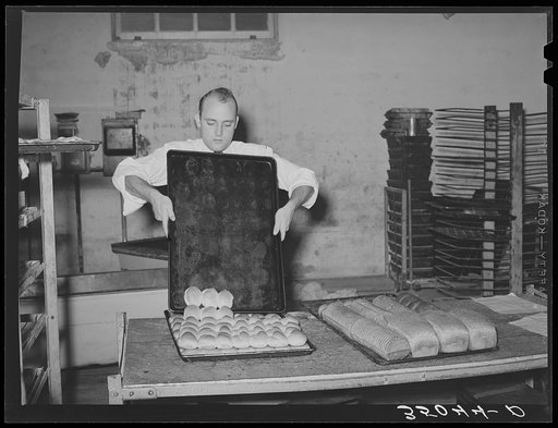 Removing rolls from tray at bakery. San Angelo, Texas