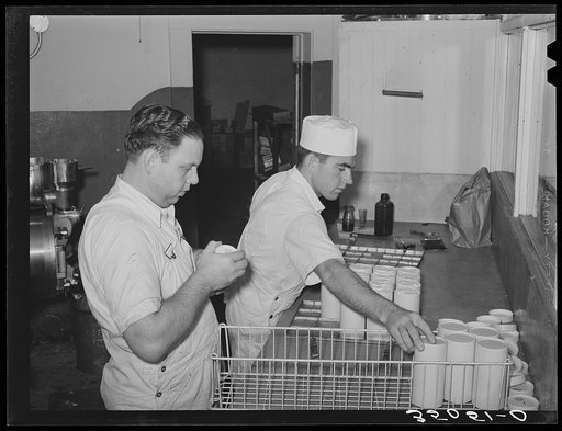Untitled image, possibly related to: Scraping surplus ice cream mix from filled cartons with a spatula. Creamery, San Angelo, Texas