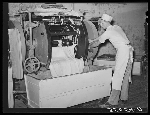Emptying the dough from mixing machine into the moveable rising vats. Bakery, San Angelo, Texas