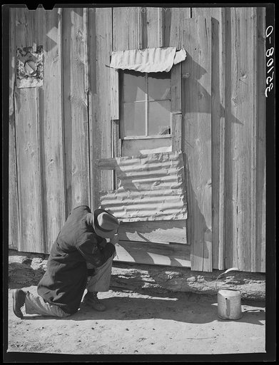 Pomp Hall, Negro tenant farmer, repairing piece of tin which covers window of his house. Creek County, Oklahoma