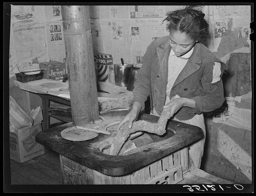 Daughter of Pomp Hall, Negro tenant farmer, putting wood in stove. Creek County, Oklahoma