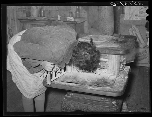 Daughter of Pomp Hall, Negro tenant farmer, blowing on fire to make it catch. Creek County, Oklahoma. See general caption number 23