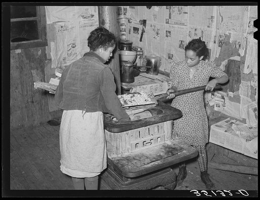 Removing ashes from stove before starting the fire in the early morning. Home of Pomp Hall, Negro tenant farmer. Creek County, Oklahoma. See general caption no. 23
