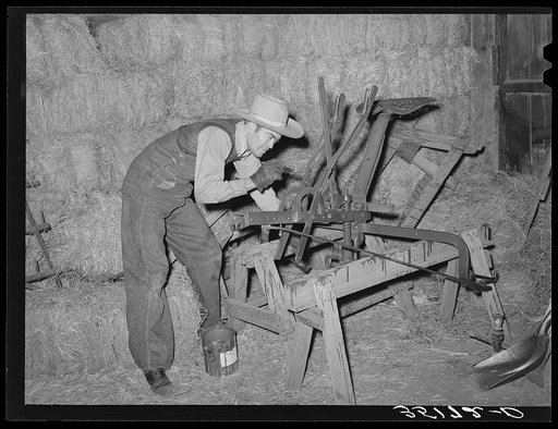 Proprietor of feed mill who also deals in secondhand farm equipment repainting a plow which he hopes to sell. Oklahoma City, Oklahoma
