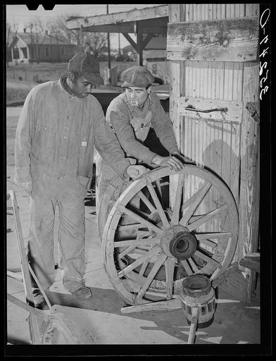 Negro farmer and blacksmith shop workman look over much-repaired wagon wheels to see if they can be made usable again. Depew, Oklahoma