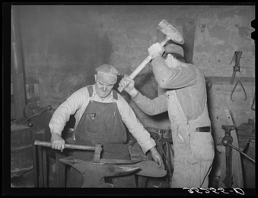 Blacksmith and helper pounding out plow point. Depew, Oklahoma