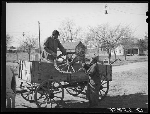 Negro farmer onloading much-repaired wagon wheel at the blacksmith shop where he hopes it can again be made serviceable. Depew, Oklahoma