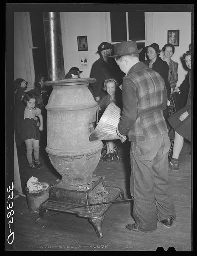 Putting coal in the stove at pie supper in Muskogee County, Oklahoma. See general caption number 24