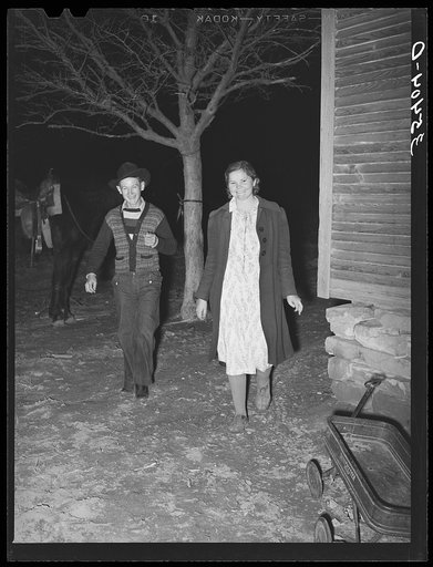 Couple coming around the corner of the house while playing the game, "Fishing for love," at play party in McIntosh County, Oklahoma. See general caption number 26