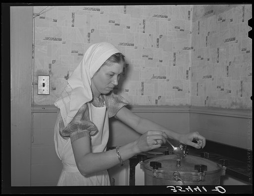 FSA (Farm Security Administration) supervisor giving a demonstration of pressure canning before a group of FSA officials at a district meeting. She is letting off steam from the pressure cooker by opening the steam cock with a spoon. San Angelo, Texas