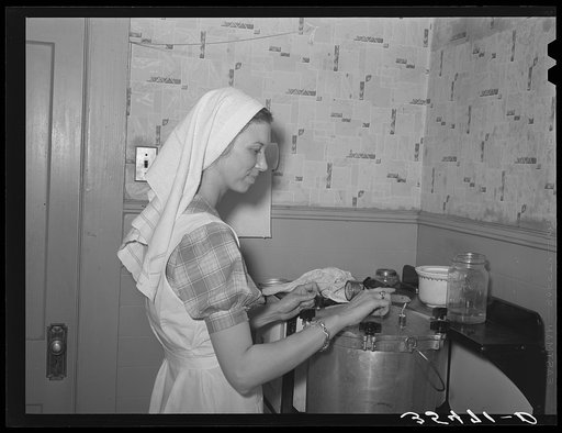 FSA (Farm Security Administration) supervisor flipping open the steam cock on top of pressure cooker during demonstration of pressure canning before a group of FSA officials at a district meeting. San Angelo, Texas