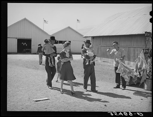 Family group passing a souvenir stand at the San Angelo Fat Stock Show. San Angelo, Texas