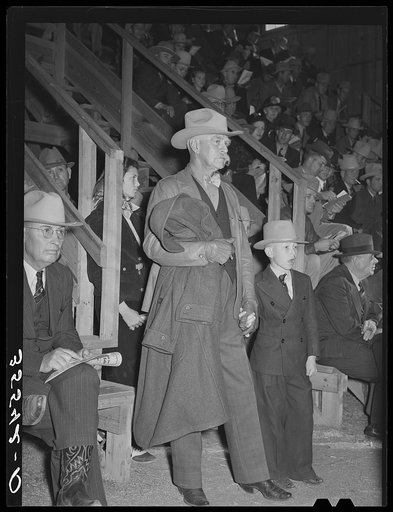 Cattleman with his grandson at auction of beef steers and breeding stock at the San Angelo Fat Stock Show. San Angelo, Texas. The Stetson hat, leather coat and boots are standard everyday wear of ranchmen. There is an old saying in Texas that a man never buys but two Stetsons, one when he gets marri