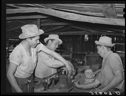 Sheep and goat shearers sharpening a blade while at work on a ranch of rehabilitation borrower in Kimble County, Texas