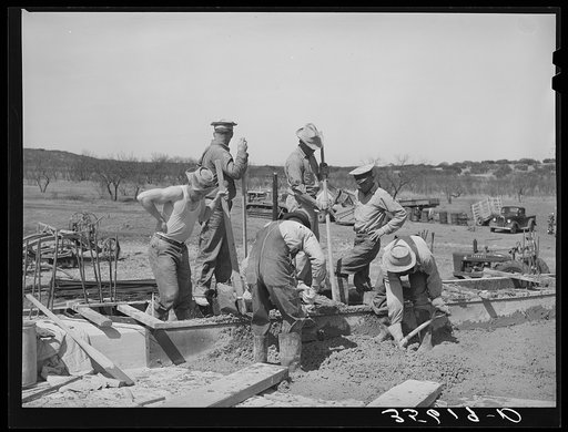 Road worker mixing concrete in Menard County, Texas