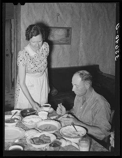 Dinner on ranch of rehabilitation borrower during goat shearing and kidding season. Kimble County, Texas. The man is a neighboring rancher who has been hired to help out with the work at this particular time.  The woman is his wife who is helping out in the house