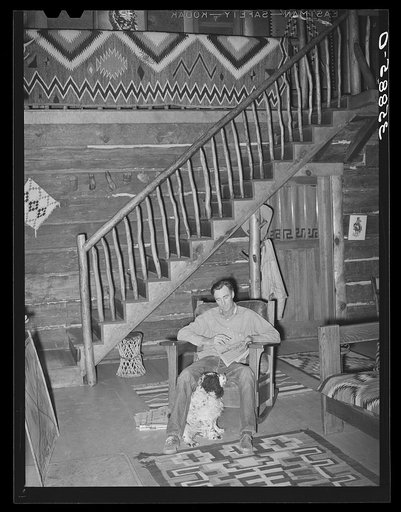 Untitled photo, possibly related to: Manager of the Navajo Lodge working a crossword puzzle with his dog at his feet. Datil, New Mexico