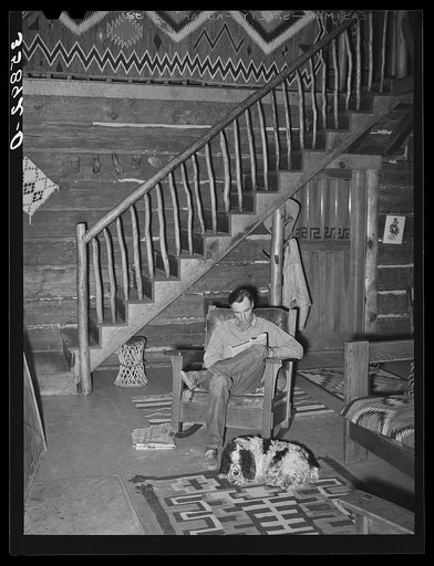 Manager of the Navajo Lodge with his dog before the fireplace on a snowy afternoon. Datil, New Mexico