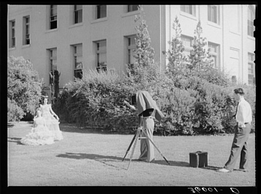 Photographer instructs high school girl in graduation play costume how to pose. Phoenix Union High School, Phoenix, Arizona