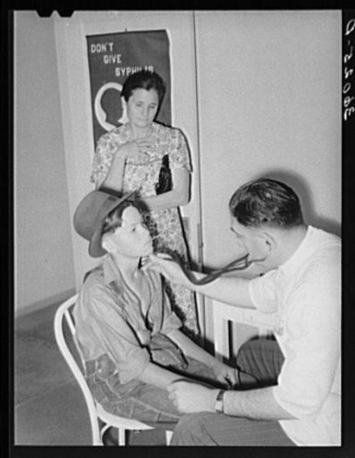 Doctor at clinic examining son of agricultural worker. Agua Fria migratory camp. Arizona