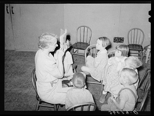WPA (Work Projects Administration) nursery teacher telling and showing picture story to children of agricultural workers at the Agua Fria migratory labor camp. Arizona