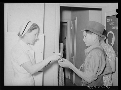 Nurse giving instructions to son of migratory laborer as to how to take medicine. Agua Fria migratory labor camp, Arizona