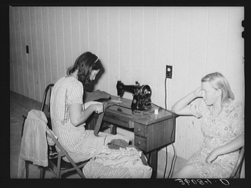 Wife of migratory agricultural laborer sewing at the Aqua Fria migratory labor camp, Arizona. These machines are rented for a nominal sum which remains in the camp fund to be used as the camp committee decides