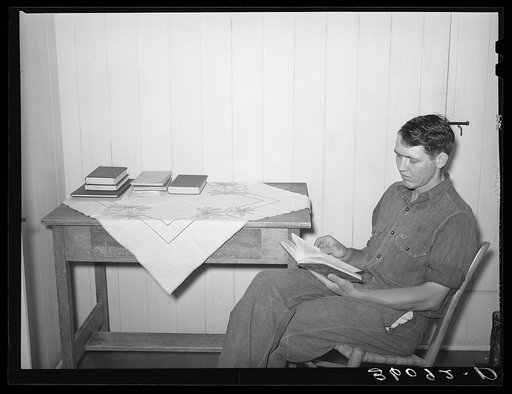 Member of the Arizona part-time farms, Chandler Unit, in bedroom of his apartment on the project studying for civil service examination in poultry culture. Maricopa County, Arizona