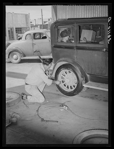 Untitled photo, possibly related to: Changing a tire at the United Producers and Consumers Cooperative service station. Phoenix, Arizona