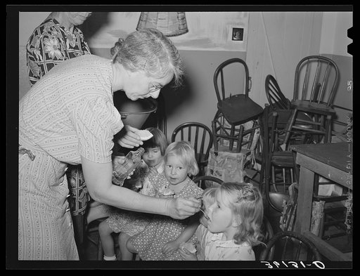Feeding children of migratory agricultural laborers cod liver oil at the WPA (Work Projects Administration) nursery school at the Agua Fria migratory labor camp. Arizona