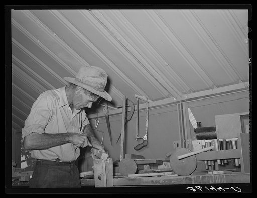 Migratory agricultural laborer making toys for the WPA (Work Projects Administration) nursery school at the Agua Fria migratory labor camp, Arizona. Farm work was slack and this man volunteered to make and repair nursery supplies during his idle time-- no pay being received