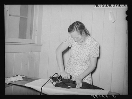 Wife of agricultural worker ironing at the Agua Fria migratory labor camp. Arizona
