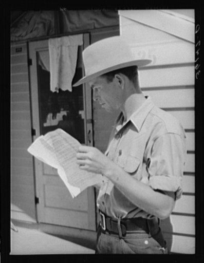 Migratory agricultural worker reading instructions on how to obtain a license to operate a truck. Agua Fria migratory labor camp, Arizona