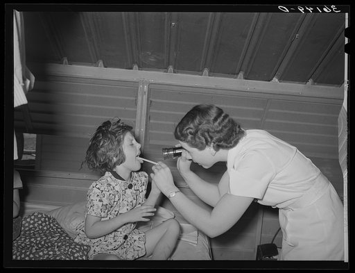Nurse examining child of migratory laborer in family metal shelter at the Agua Fria migratory labor camp. Arizona