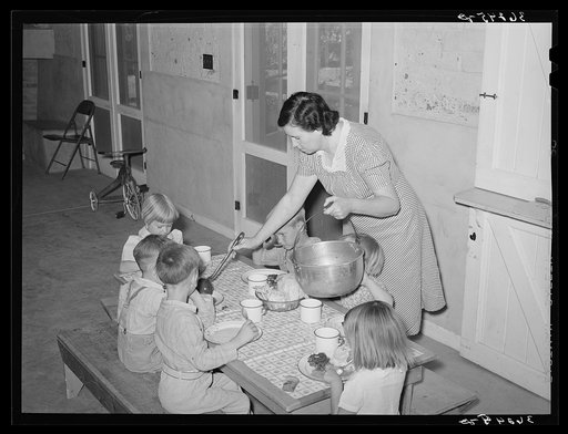 WPA (Work Projects Administration) nursery school supervisor "helping the plates" of the children who have their lunches at the school. Casa Grande Valley Farms, Pinal County, Arizona