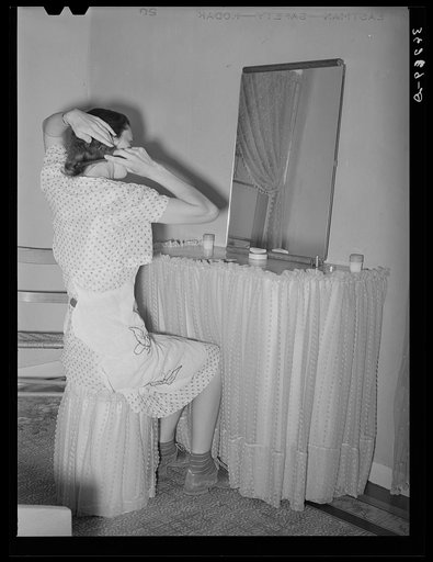 Wife of member of the Casa Grande Valley Farms sitting in front of dressing table in her home. Pinal County, Arizona