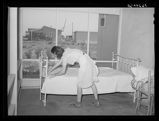 Untitled photo, possibly related to: Wife of member of the Casa Grande Valley Farms, Pinal County, Arizona making up bed on her porch. These large porches on all the homes are used for auxillary living quarters