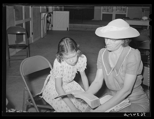 Reading the lesson from the Bible at the Sunday school at the Community house of the Casa Grande Valley Farms. Pinal County, Arizona