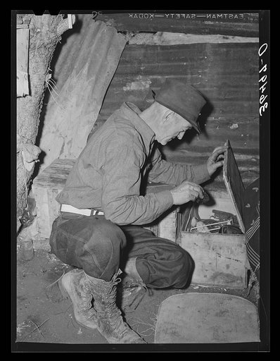 Eugene Davis, gold prospector, looking into chest where he has stored his belongings. Pinos Altos, New Mexico