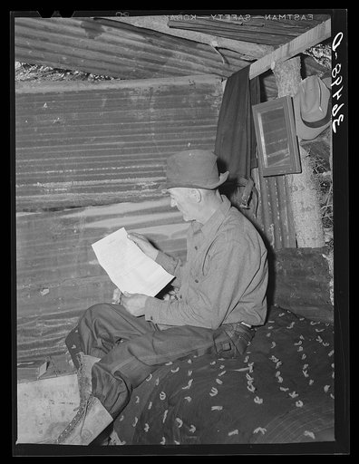 Eugene Davis, gold prospector, reading over location notice form which must be filed along with mining claim. Pinos Altos, New Mexico