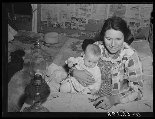 Mrs. Holley holding her baby while playing Fforty-two at party after literary society meeting. Pie Town, New Mexico. Mrs. Holley and her husband farmed in Texas before homesteading in Pie Town, New Mexico