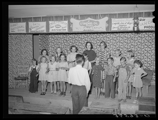 Children at the private school held in the Farm Bureau building keeping time with homemade musical instruments with a phonograph. Pie Town, New Mexico