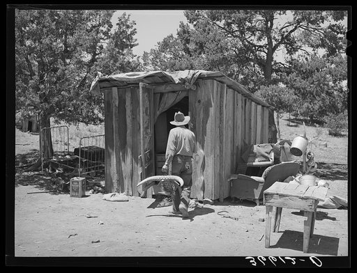 Faro Caudill taking household articles into shed for storage while he moves his dugout. Pie Town, New Mexico