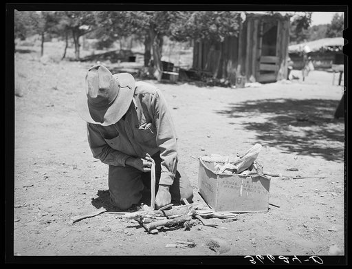 Untitled photo, possibly related to: Faro Caudill building a fire to cook dinner while he moves his dugout. Pie Town, New Mexico