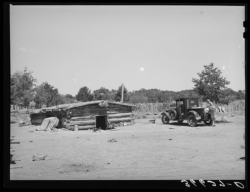 Dugout home of the Caudills with Mrs. Caudill standing by the pickup truck which her husband bought this summer. Pie Town, New Mexico