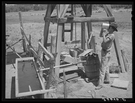 Farm boy drinking at the well. Pie Town, New Mexico
