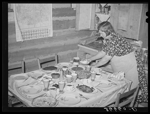 Mrs. Bill Stagg, homesteader's wife, putting the coffee on the table for dinner. For dinner there was home-cured ham and gravy, pinto beans, corn, homemade pickles, homegrown tomatoes, homemade bread and hot biscuits, fruit salad, cake, two kinds of pie, milk and coffee. Pie Town, New Mexico