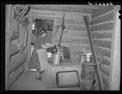 Mrs. Bill Stagg drawing water from her well, which is in enclosed porch in her log house. Pie Town, New Mexico