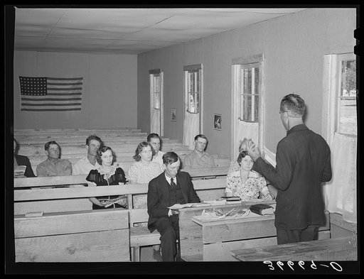 Mr. Whinery, homesteader and licensed preacher, reading the Sunday School lesson in the Farm Bureau building. Pie Town, New Mexico. Mr. Whinery donates his services as a preacher to the church